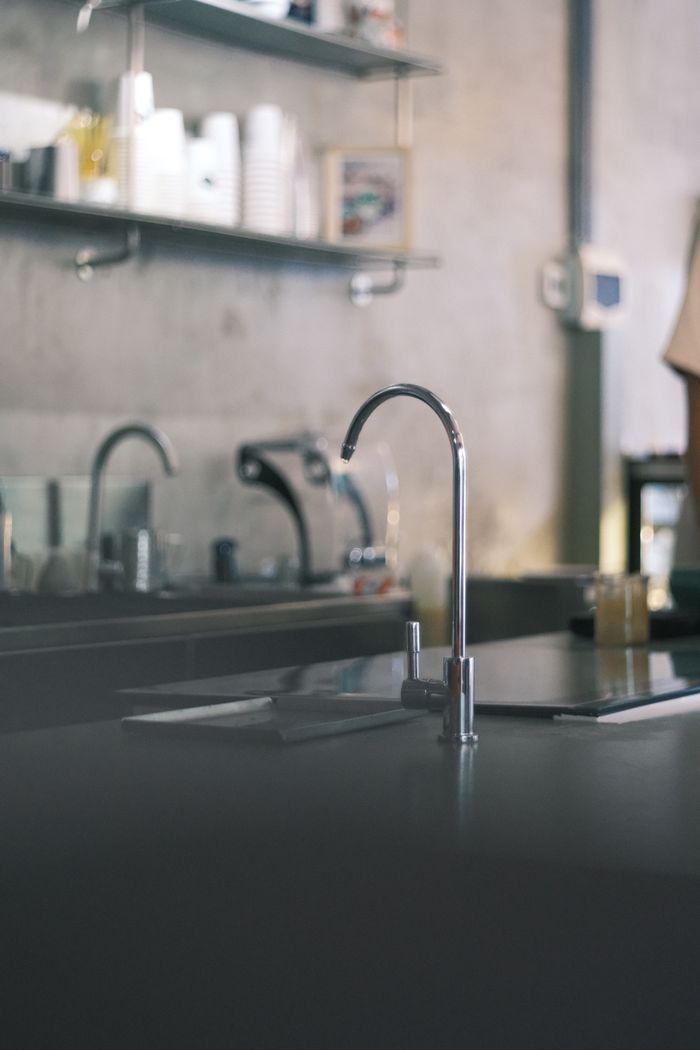 Sleek minimalist kitchen interior featuring a chrome faucet and industrial design elements.
